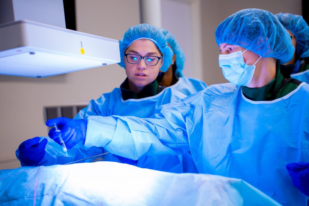 CRNAs injecting covered patient with syringe 